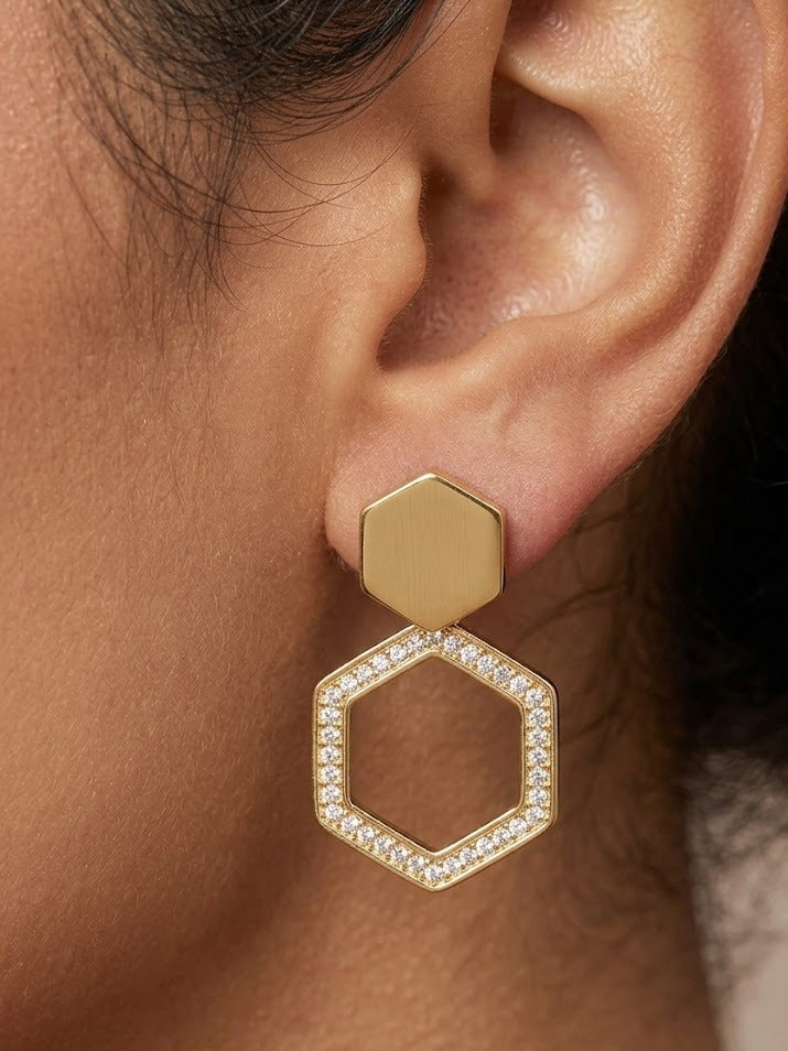 Gold hexagonal earring with clear stones worn by a person